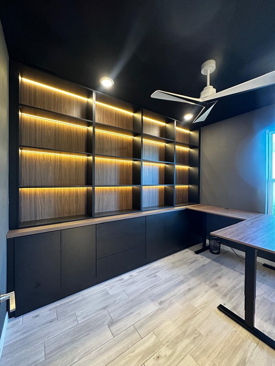 Custom black and wood home office cabinetry with integrated lighting